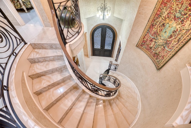 staircase featuring a textured wall, arched walkways, and french doors