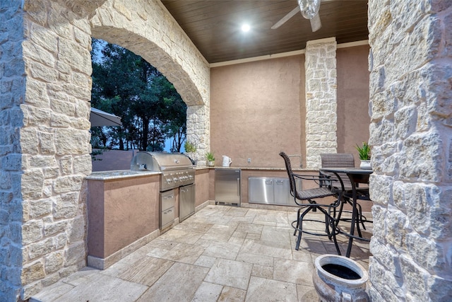 view of patio with an outdoor kitchen, a ceiling fan, and area for grilling