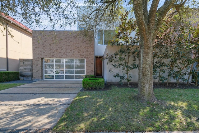 view of front facade with concrete driveway, a front lawn, an attached garage, and brick siding