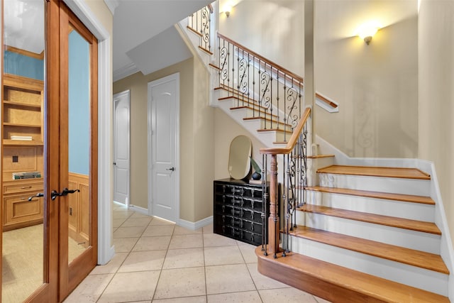 stairs featuring tile patterned flooring, crown molding, and wainscoting