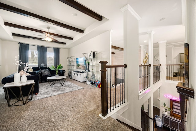 carpeted living area with ceiling fan, beamed ceiling, and ornate columns