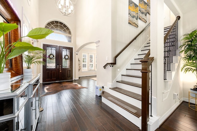 entryway with dark wood-type flooring, stairway, baseboards, and an inviting chandelier