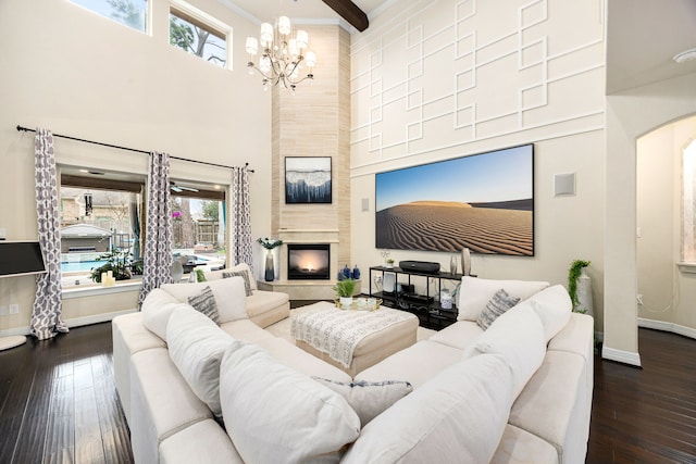 living area featuring a high ceiling, baseboards, dark wood finished floors, and a tiled fireplace