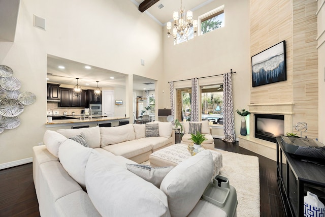 living room featuring visible vents, baseboards, a tile fireplace, dark wood-type flooring, and a chandelier