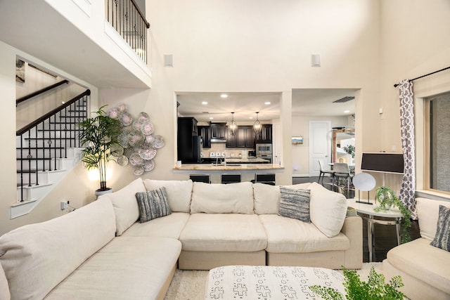 living area featuring visible vents, a high ceiling, stairway, and recessed lighting