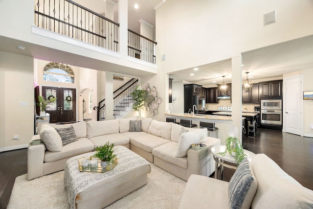 living room featuring arched walkways, recessed lighting, stairway, light wood-style floors, and baseboards