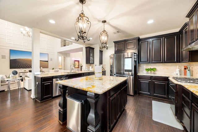 kitchen with a kitchen island, stainless steel appliances, dark brown cabinets, pendant lighting, and a notable chandelier