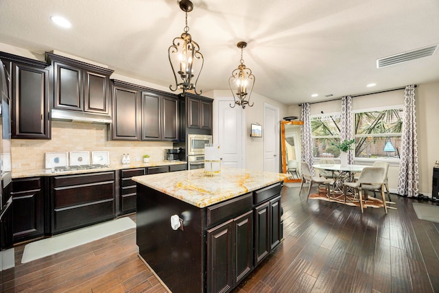 kitchen featuring visible vents, appliances with stainless steel finishes, a center island, dark brown cabinets, and pendant lighting