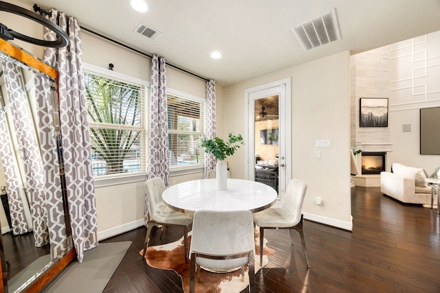 dining space with baseboards, a fireplace, visible vents, and dark wood-type flooring