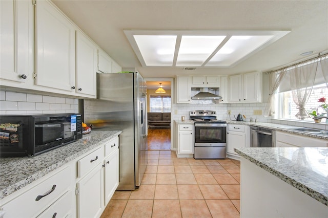 kitchen with white cabinets, wall chimney range hood, and stainless steel appliances