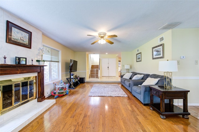 living area with light wood-style floors, baseboards, visible vents, and a tile fireplace