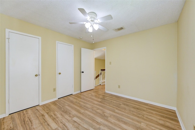 unfurnished bedroom with a textured ceiling, ceiling fan, visible vents, baseboards, and light wood finished floors