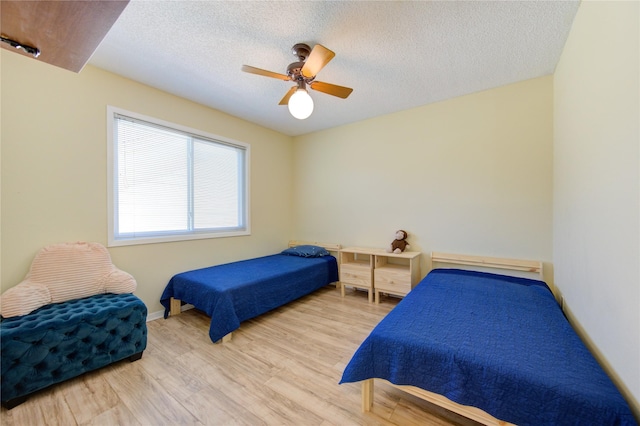 bedroom with ceiling fan, a textured ceiling, and wood finished floors