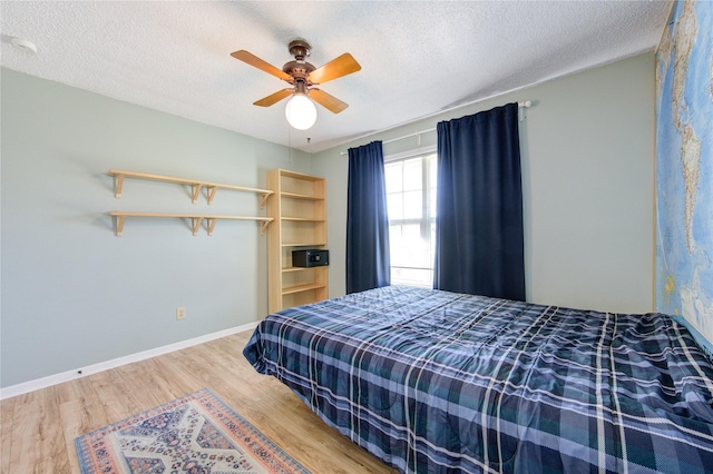 bedroom featuring ceiling fan, a textured ceiling, baseboards, and wood finished floors