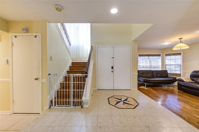 foyer with light tile patterned flooring, stairway, and baseboards