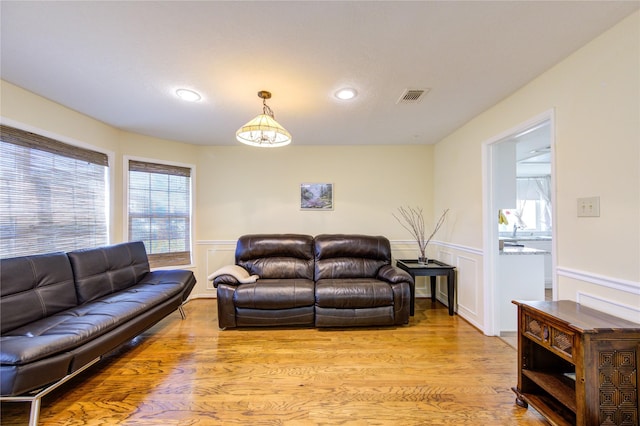 living area featuring light wood-style flooring, wainscoting, and visible vents