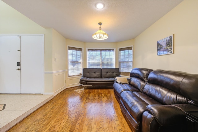 living room with wainscoting, a decorative wall, and wood finished floors