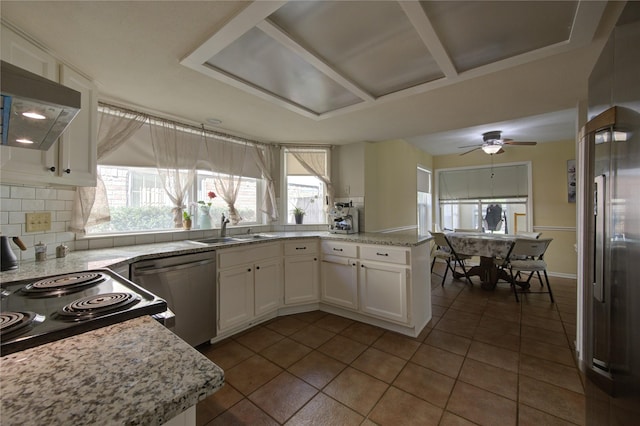 kitchen with white cabinets, a peninsula, stainless steel dishwasher, a sink, and exhaust hood