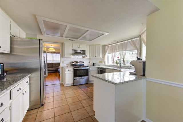 kitchen featuring appliances with stainless steel finishes, a sink, wall chimney range hood, white cabinetry, and backsplash