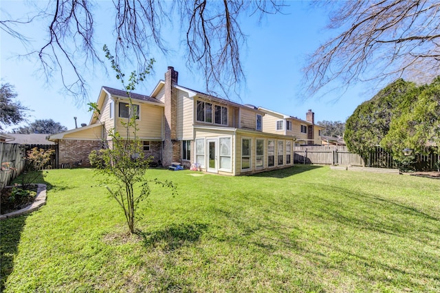 rear view of property with a sunroom, a fenced backyard, a chimney, and a lawn