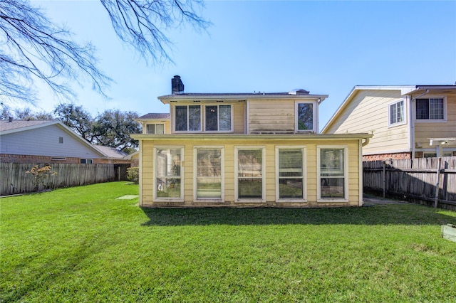 rear view of house with a fenced backyard, a lawn, and a chimney