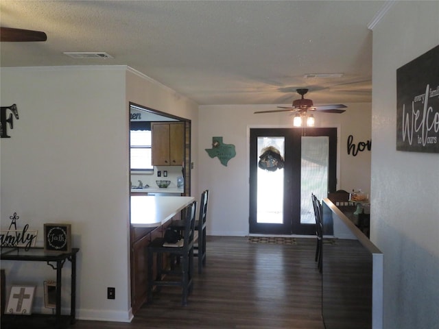 dining room with baseboards, visible vents, dark wood finished floors, a ceiling fan, and ornamental molding