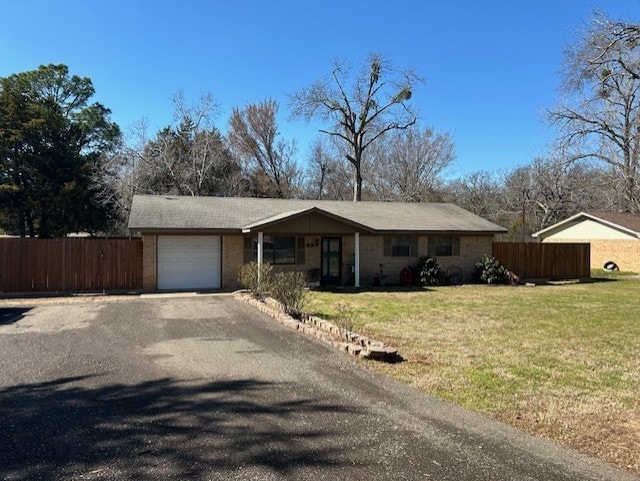 ranch-style home featuring aphalt driveway, a front lawn, fence, and an attached garage