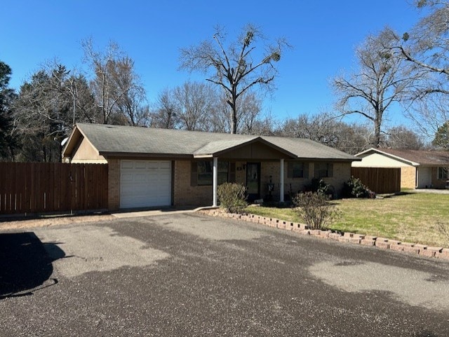 single story home featuring an attached garage, driveway, fence, and a front yard