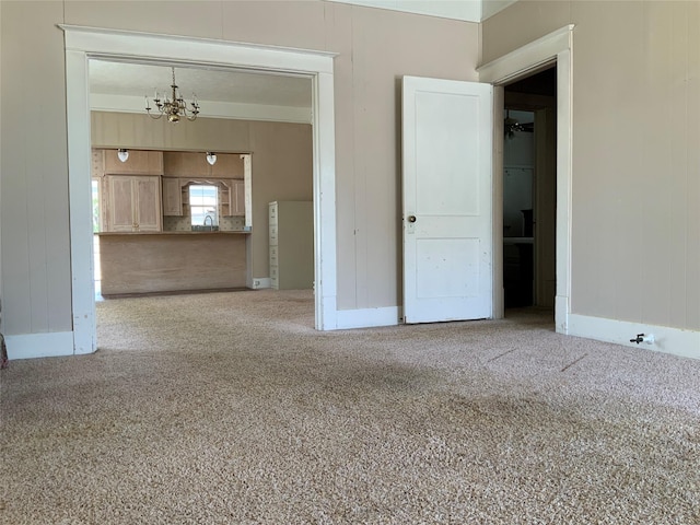 unfurnished living room with a chandelier, carpet, wood walls, and baseboards