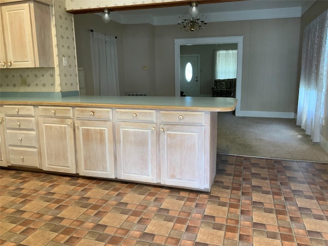 kitchen featuring a notable chandelier, light countertops, dark carpet, a peninsula, and baseboards