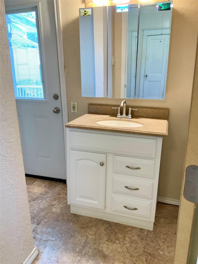 bathroom featuring a textured wall, vanity, and baseboards