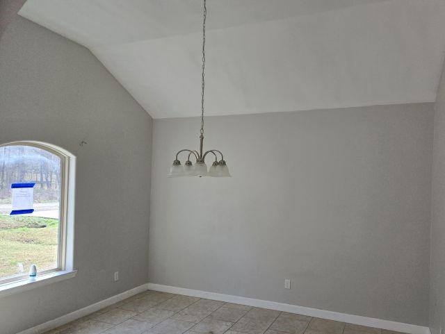 unfurnished dining area featuring lofted ceiling, baseboards, and a notable chandelier