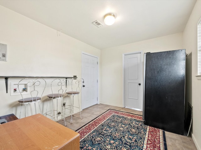 kitchen featuring freestanding refrigerator, visible vents, and baseboards