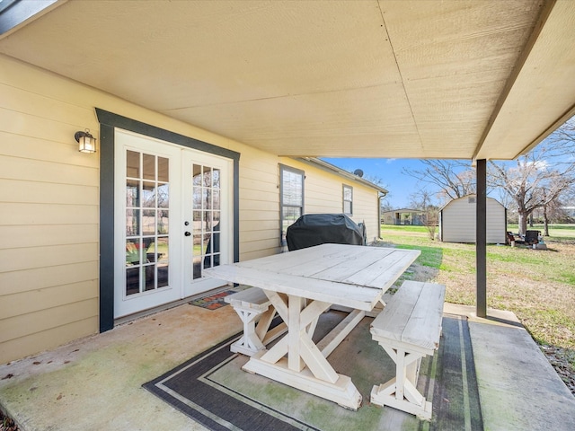 view of patio / terrace featuring french doors, a storage unit, grilling area, outdoor dining space, and an outdoor structure