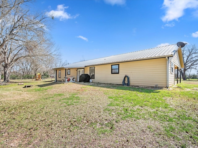 back of property with metal roof and a yard