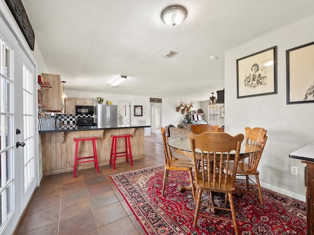 dining space featuring dark tile patterned flooring, french doors, visible vents, and baseboards