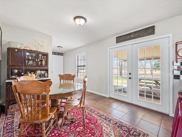 tiled dining room featuring baseboards and french doors