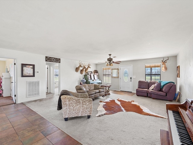 living room with carpet, visible vents, and a ceiling fan