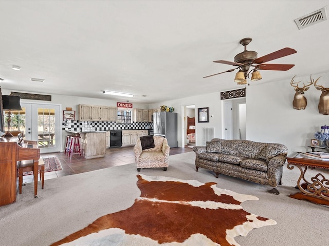 living room featuring light tile patterned floors, visible vents, french doors, and light colored carpet