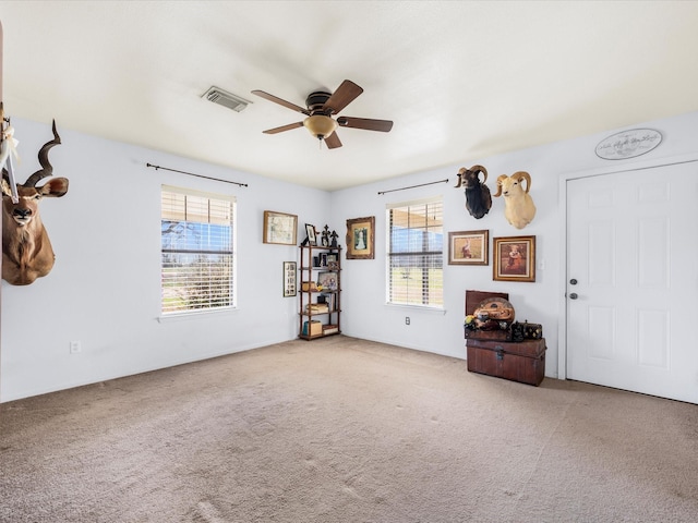 interior space with carpet, visible vents, and a ceiling fan