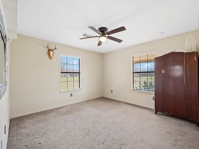 unfurnished room featuring light carpet, crown molding, a ceiling fan, and a healthy amount of sunlight