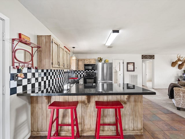 kitchen featuring tasteful backsplash, dark countertops, a breakfast bar, decorative light fixtures, and black appliances