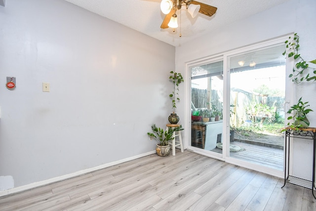 empty room with light wood-style floors, ceiling fan, baseboards, and a textured ceiling