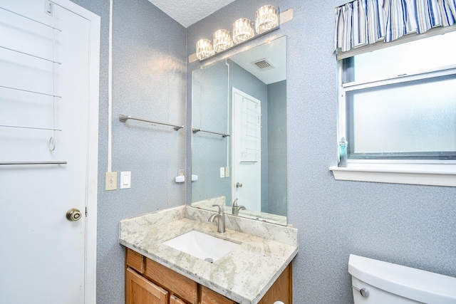 bathroom with visible vents, vanity, and toilet