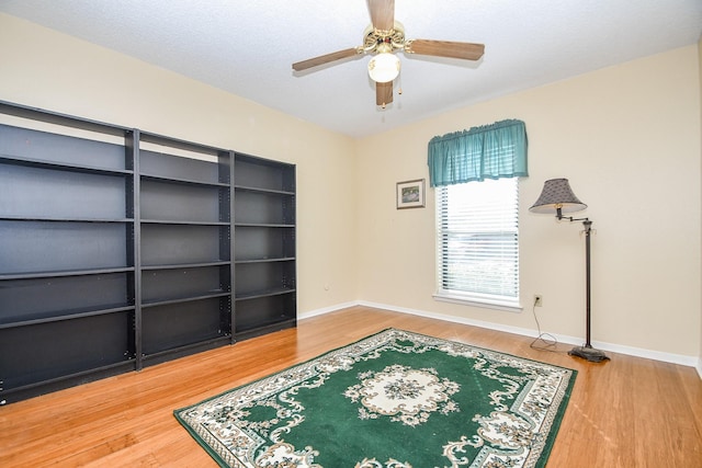 interior space featuring ceiling fan, baseboards, and wood finished floors