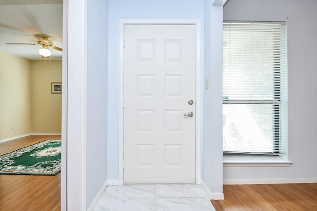 entryway with ceiling fan and baseboards