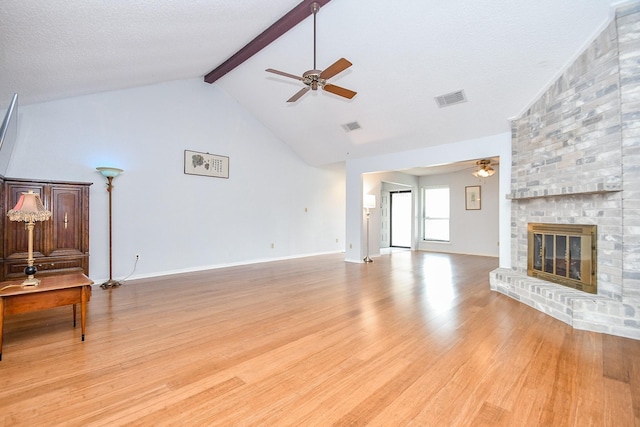 living area featuring visible vents, a ceiling fan, beamed ceiling, light wood-type flooring, and a fireplace