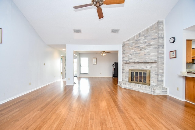 unfurnished living room featuring visible vents, a fireplace, light wood finished floors, and ceiling fan