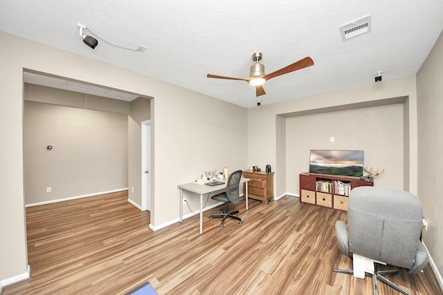 office featuring baseboards, visible vents, ceiling fan, a textured ceiling, and light wood-style floors