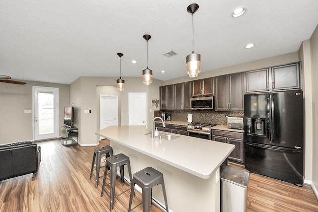 kitchen featuring a center island with sink, visible vents, appliances with stainless steel finishes, light countertops, and a sink